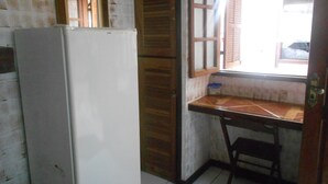 A kitchen with a refrigerator, wooden cabinets, a window with shutters, and a tiled floor. - Gohouse - Suite Tonelero 01 (Rio de Janeiro)