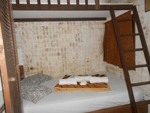 Ein Stockbett mit einer Holzleiter, einem Kissen mit ZEBRA-MUSTER und einem Handtuch auf der Matratze.