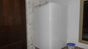 Une cuisine de taille réduite avec un réfrigérateur blanc, une porte en bois et un mur recouvert de carreaux.