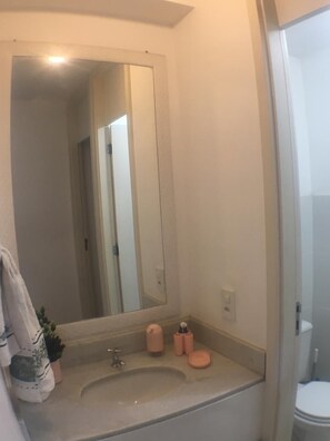 A bathroom with a large mirror, a sink, and a toilet.
