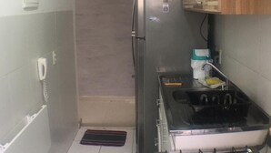 A compact kitchen with a refrigerator, stove, and a small sink.