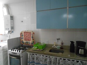 A kitchen with a gas stove, a sink, and a coffee maker. - Gohouse - Siqueira 703 (Rio de Janeiro)