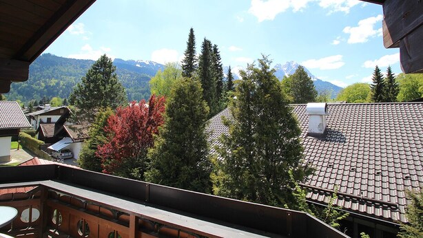 A view from a balcony overlooking a mountainous landscape with trees and houses. - Solinda (Garmisch-Partenkirchen)
