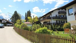 A two-story building with balconies, a wooden fence, and a car parked in front. - Solinda (Garmisch-Partenkirchen)