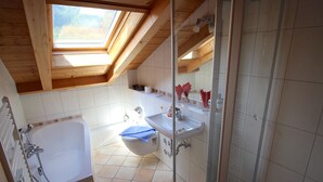 A bathroom with a skylight, a bathtub, a shower, and a toilet. - Solinda (Garmisch-Partenkirchen)