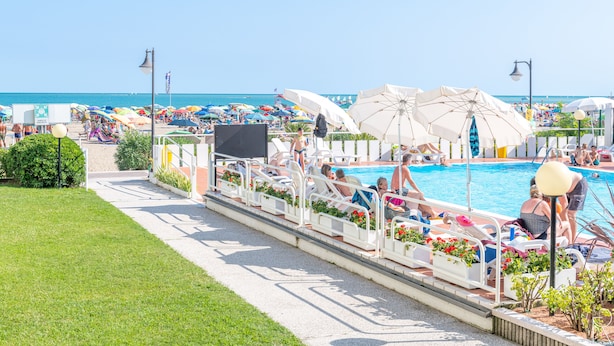 Un área junto a la piscina con sillones de descanso y sombrillas, una piscina y una vista despejada del océano.