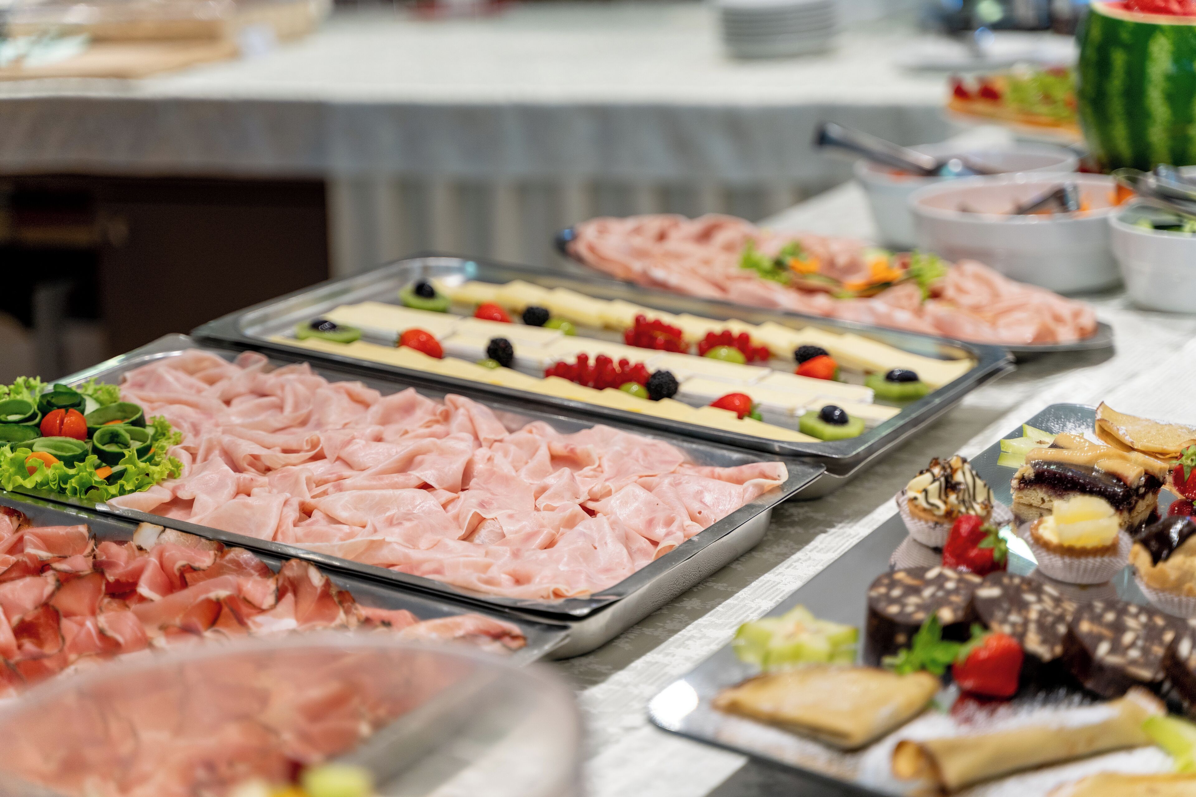 A buffet with various food items including meats, fruits, and desserts.