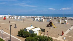 Una playa con numerosas cabañas, un parque infantil y una vista despejada del mar.