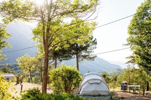 A tent in a forested area with mountains in the background. - Camping RCN Les Collines de Castellane (La Garde)
