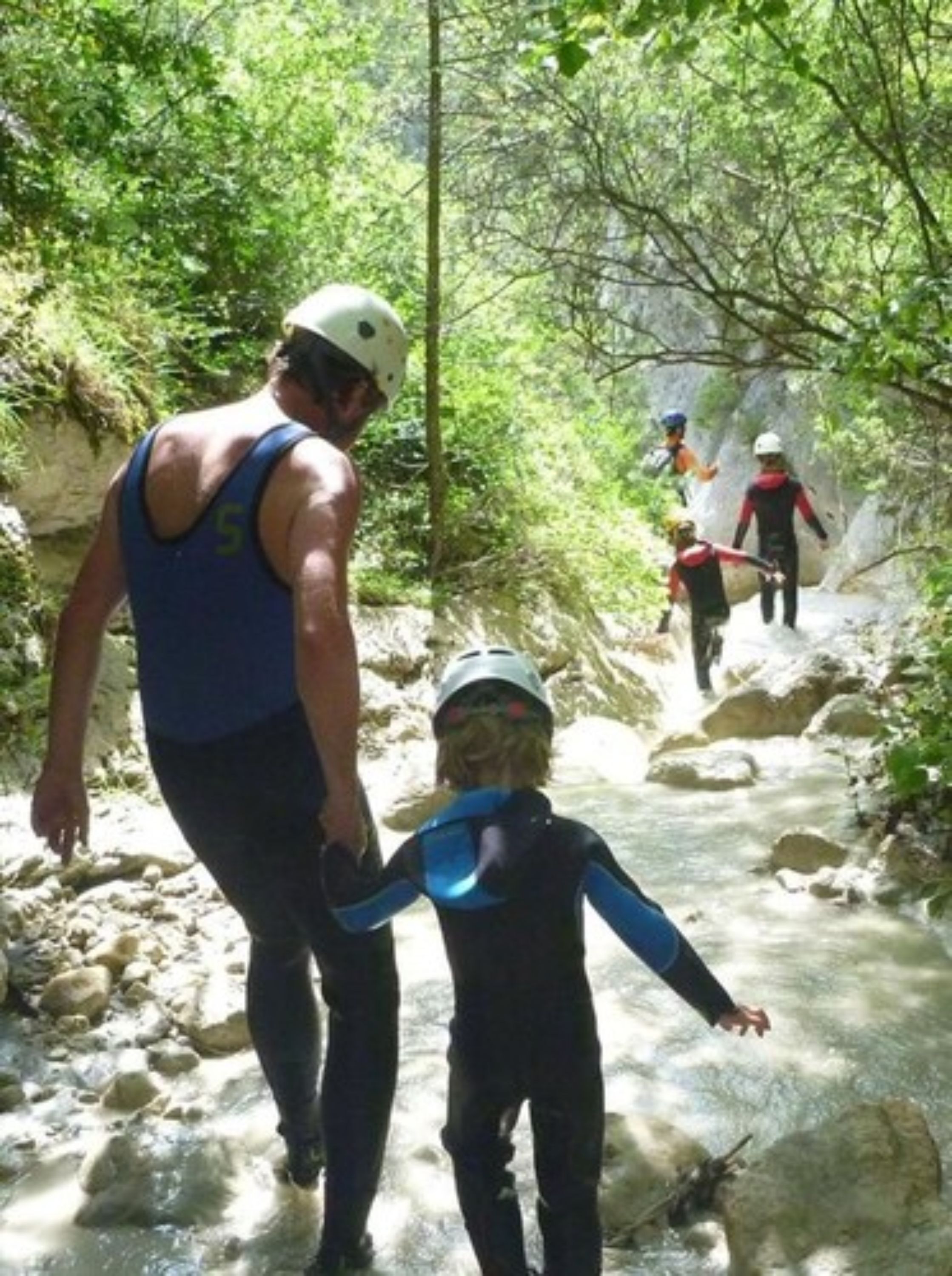 A group of people hiking in a forested area with a stream.