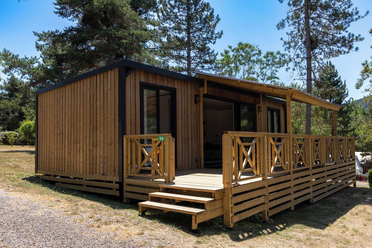 Een houten vakantiehuisje met een terras en een overdekte veranda.