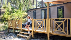 A wooden deck leading to a cabin with a covered patio area. - Camping RCN Les Collines de Castellane (La Garde)