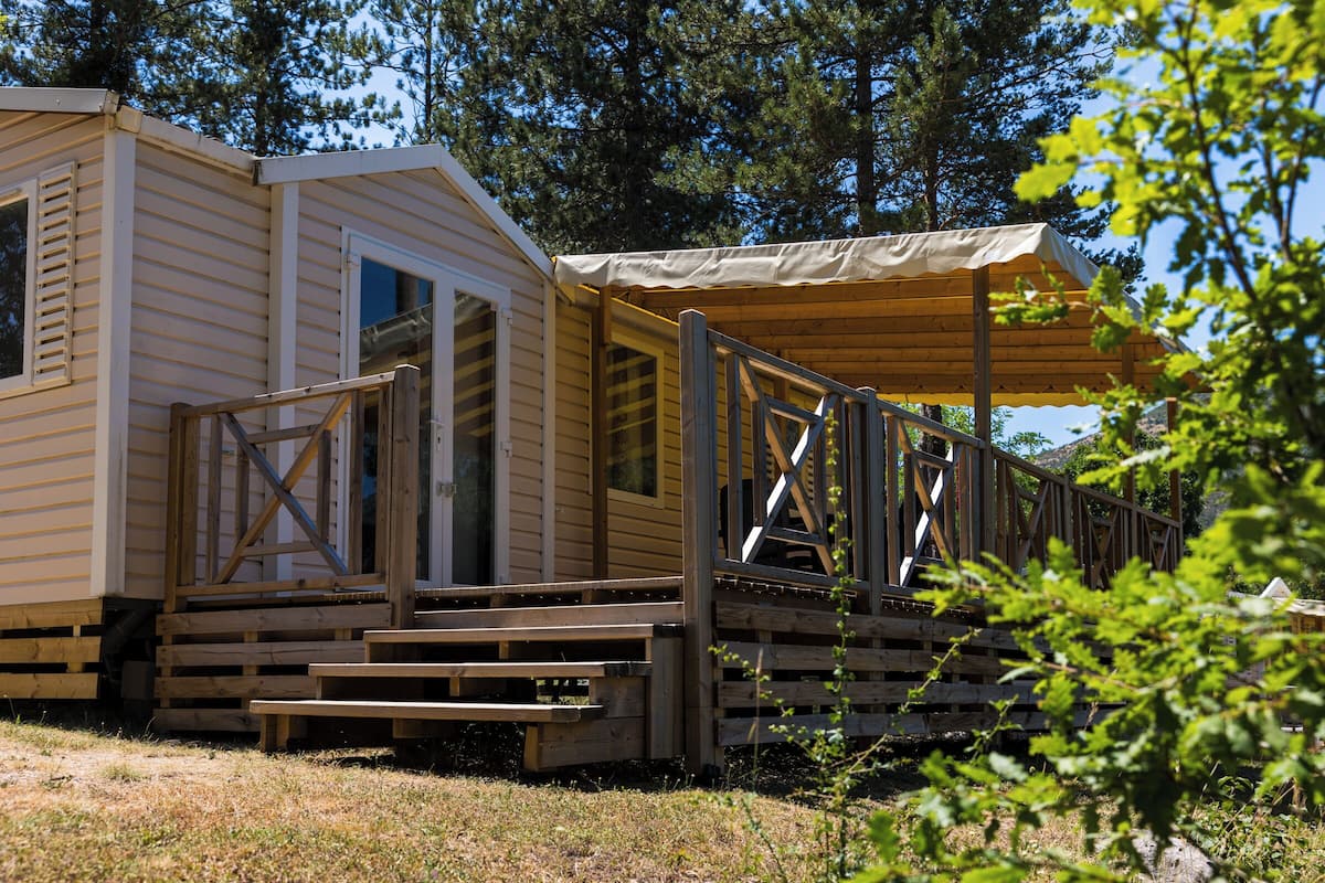 Een houten vakantiehuisje met een veranda en een overdekt terras.