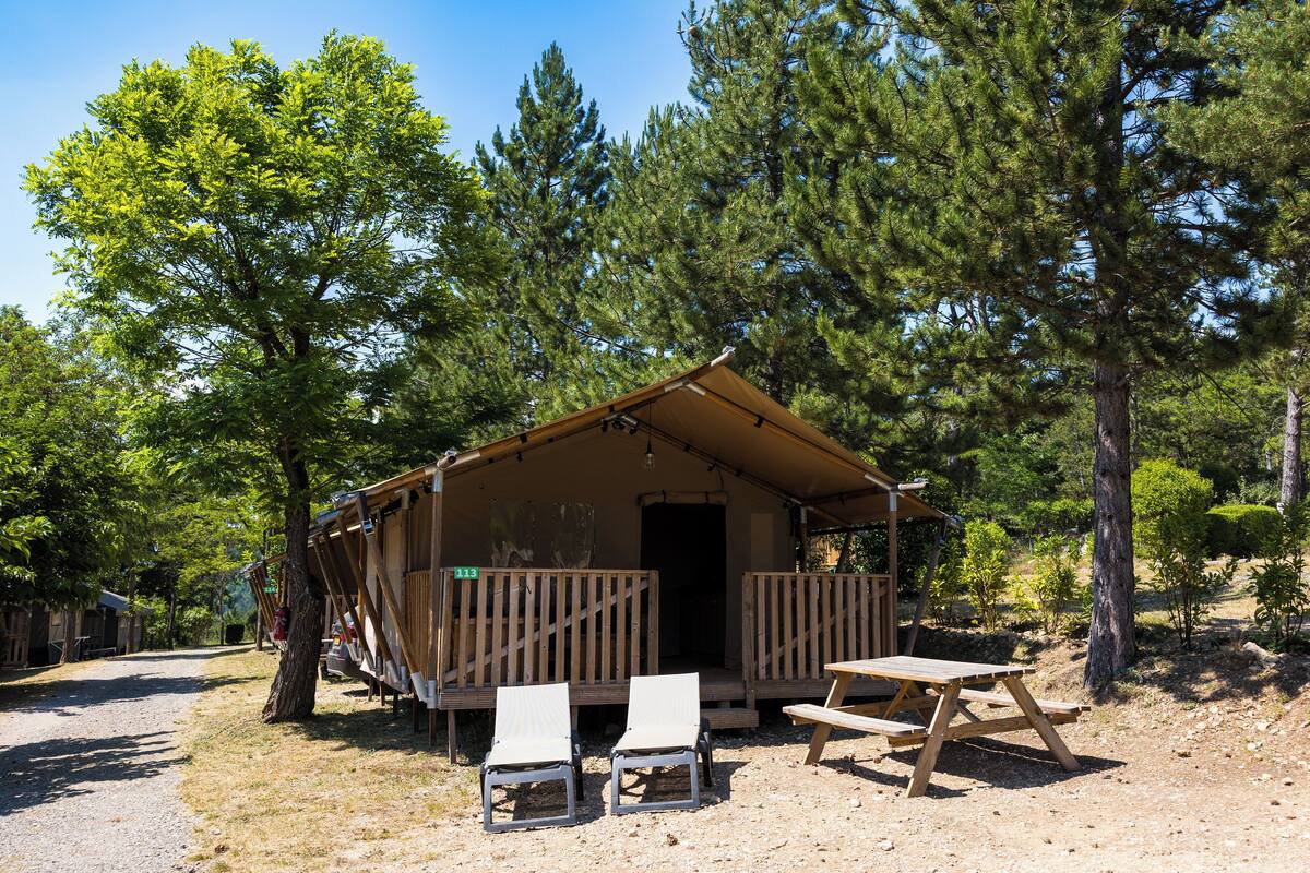 Een klein huisje met een veranda, twee stoelen en een picknicktafel.