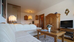A living room with a sofa, a coffee table, a television, and a wooden cabinet. - Wettersteinblick (Garmisch-Partenkirchen)