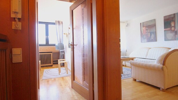 A living room with a sofa, a coffee table, and a door leading to another room. - Wettersteinblick (Garmisch-Partenkirchen)