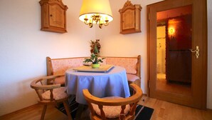 A dining area with a table set for two, a bench, and a chandelier. - Wettersteinblick (Garmisch-Partenkirchen)