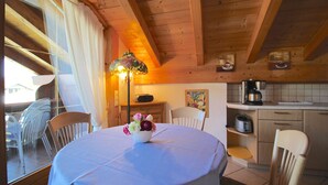 Un coin repas accueillant avec une table ronde, des chaises, un arrangement floral en guise de centre de table et une vue sur la cuisine.
