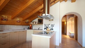 Une cuisine moderne avec des poutres en bois, un îlot central et des ustensiles de cuisine suspendus.