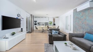 A modern living room with a flat-screen TV, a sofa, and a coffee table. - Villa Almedina - perfect holiday destination with a pool, whirlpool and sauna by MyWaycation (Ljutici)