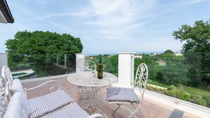 A balcony with a round table, two chairs, and a bottle of wine. - Villa Almedina - perfect holiday destination with a pool, whirlpool and sauna by MyWaycation (Ljutici)