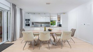 Uma cozinha moderna com armários brancos, uma ilha central e um espaço de refeições com quatro cadeiras.