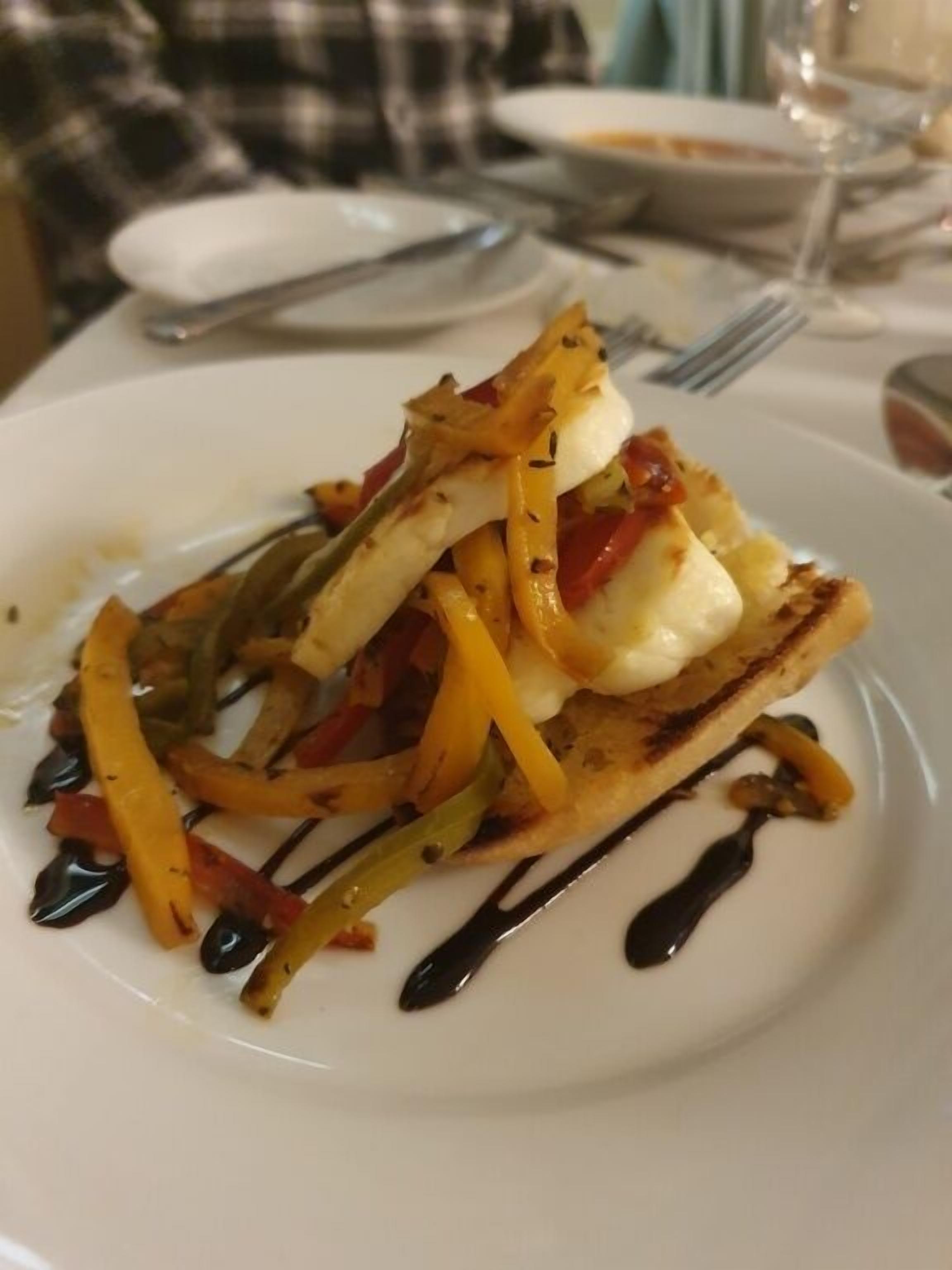 A plate of food with grilled vegetables and a piece of bread topped with cheese.