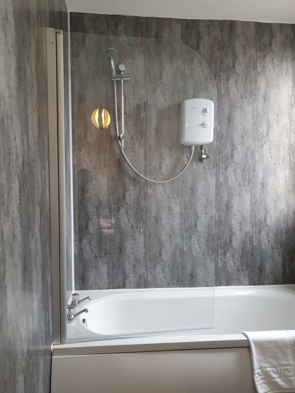 A modern bathroom with a bathtub, a handheld showerhead, and a wall-mounted control panel.
