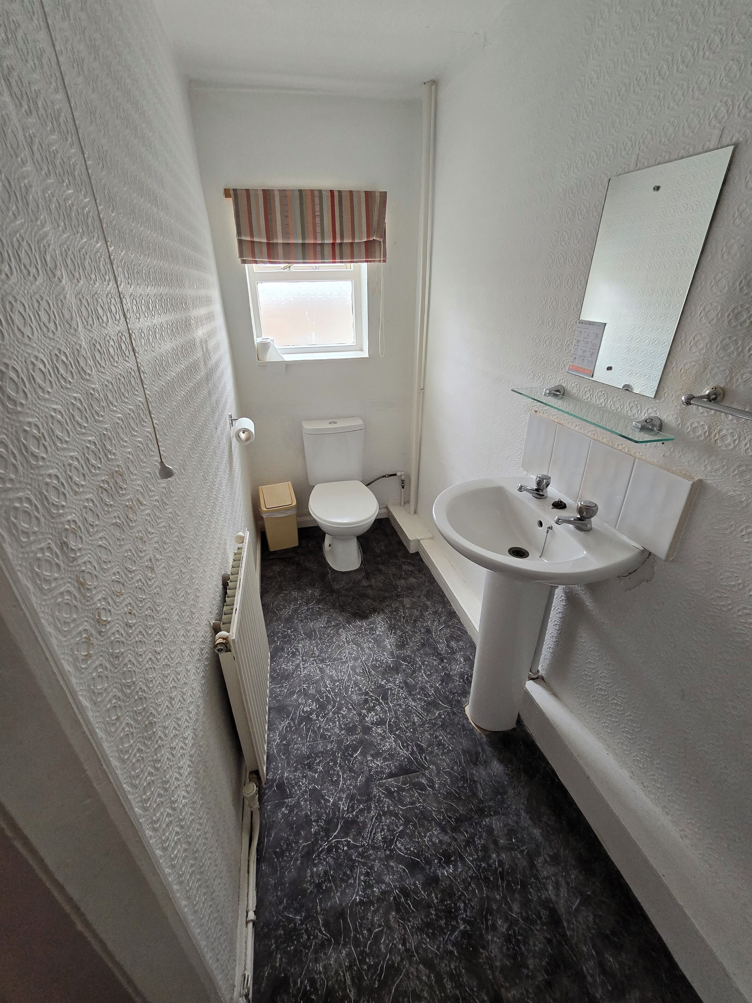 A compact bathroom with a toilet, a sink, and a window.