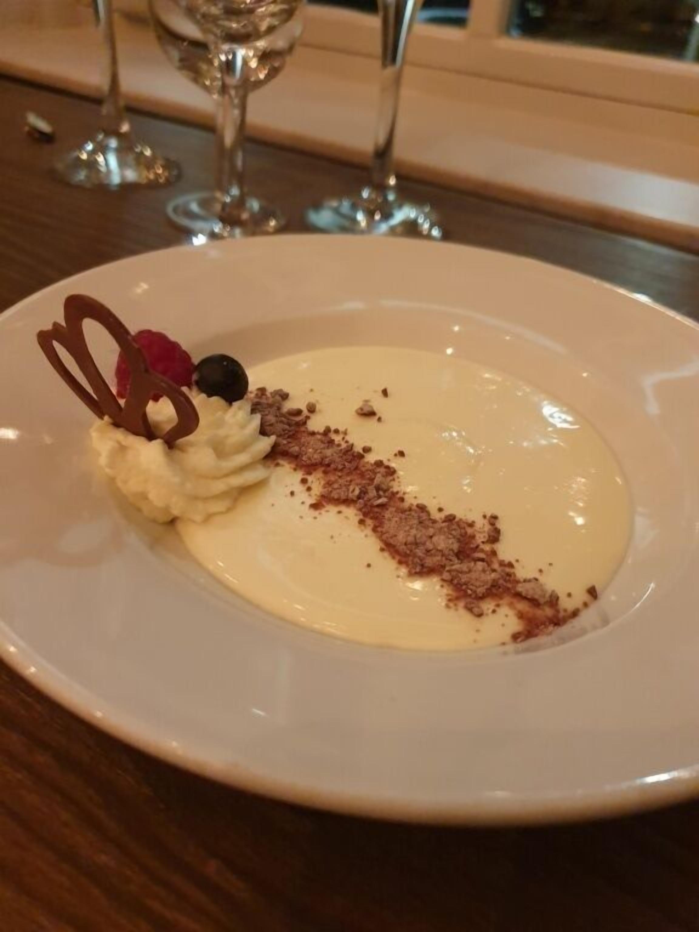 A dessert plate with a creamy base, chocolate shavings, and a decorative chocolate heart.