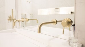A bathroom with a white sink, gold faucets, and a mirror. - House of Amstel (Amsterdam)