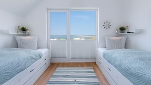 A bedroom with two beds, a large window, and a view of the sea. - Viktoria's Baltic Lounge - First row on the water, sauna, fireplace, balcony (Olpenitz)