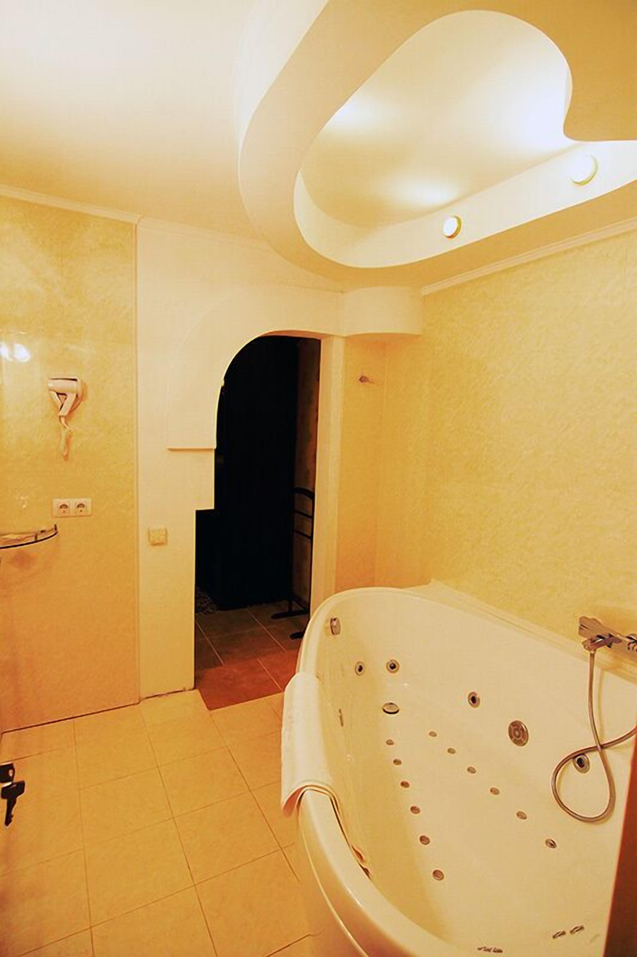 A bathroom with a large bathtub, a shower, and a toilet. There is a towel rack and a door with a handle.