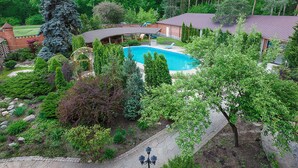 Un patio trasero con piscina, rodeado de varios árboles y un edificio de ladrillo.