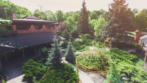 Un jardín con un pabellón, un edificio de ladrillo y árboles altos.