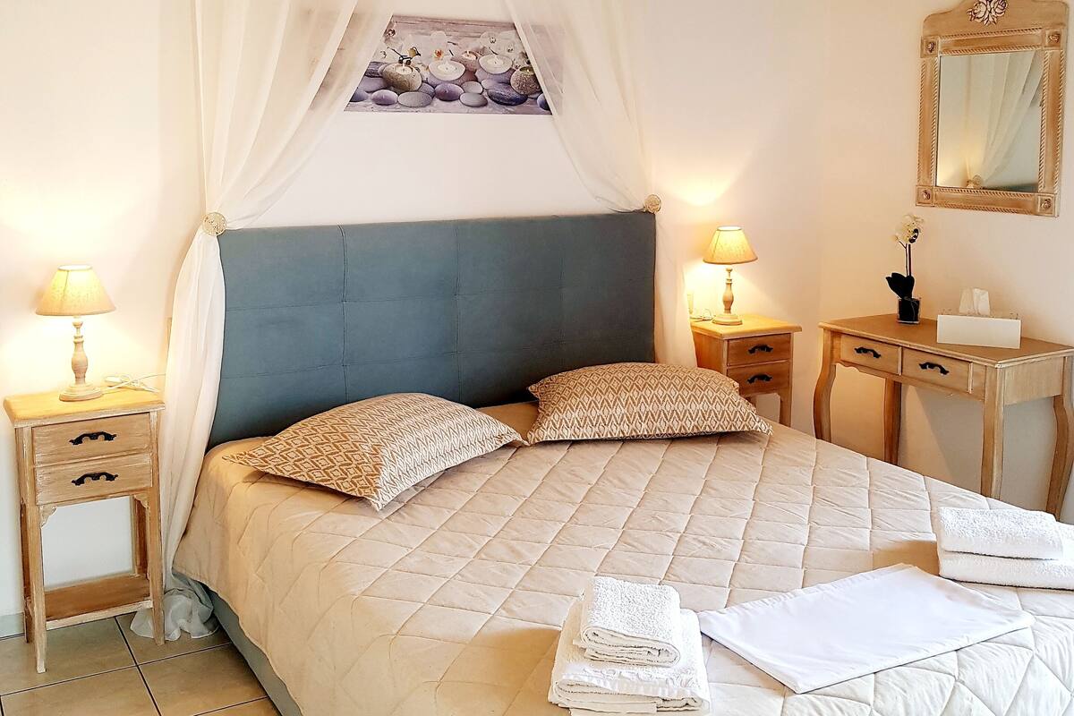 Ein Schlafzimmer mit einem Bett, zwei Nachttischen, einem Spiegel und einer Deckenleuchte.