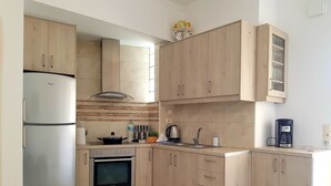 A modern kitchen with wooden cabinets, a stainless steel refrigerator, a Bosch oven, and a coffee maker. - Emmanouil Airport Beach Apartment (Hersonissos)