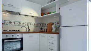 Eine kleine Küche mit weißen Schränken, einem Herd, einer Spüle und einem Kühlschrank.