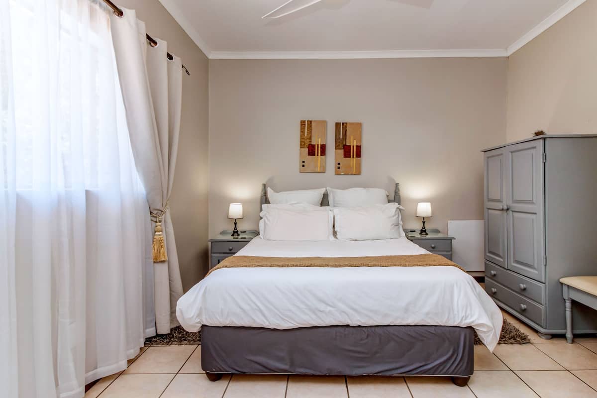A bedroom with a bed, nightstands, a wardrobe, and two wall-mounted artworks.