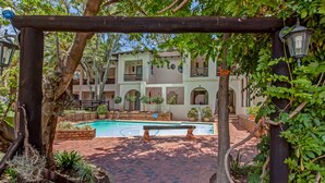 A courtyard with a swimming pool, surrounded by brick pathways and greenery. - Dalberry Guest House (Sandton)