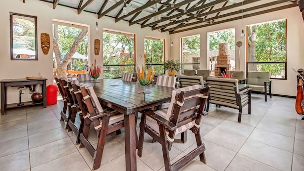 A spacious dining area with a large wooden table, striped chairs, and a brick fireplace. - Dalberry Guest House (Sandton)