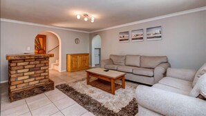 A living room with a brick fireplace, a beige sofa, and a coffee table. - Dalberry Guest House (Sandton)