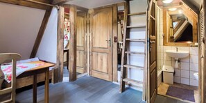 A room with a wooden chair, a table, a wardrobe, and a bathroom with a sink and toilet. - Góralski Dwór (Koscielisko)