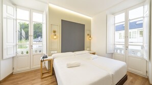 Hotellihuone, jossa on suuri sänky, yöpöydät ja näkymä ikkunoista.