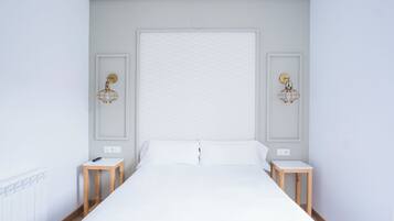 Un dormitorio minimalista con una cama grande, dos mesitas de noche e iluminación empotrada en la pared.
