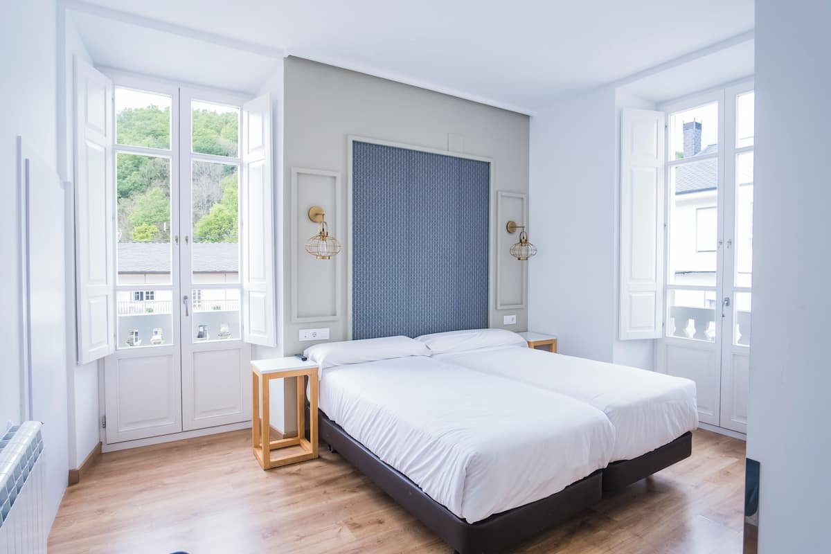 Un dormitorio con una cama grande, dos mesitas de noche, un ventanal y vistas al exterior.