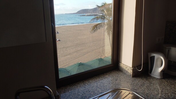 A kitchen with a view of a beach, a coffee maker, and a microwave.