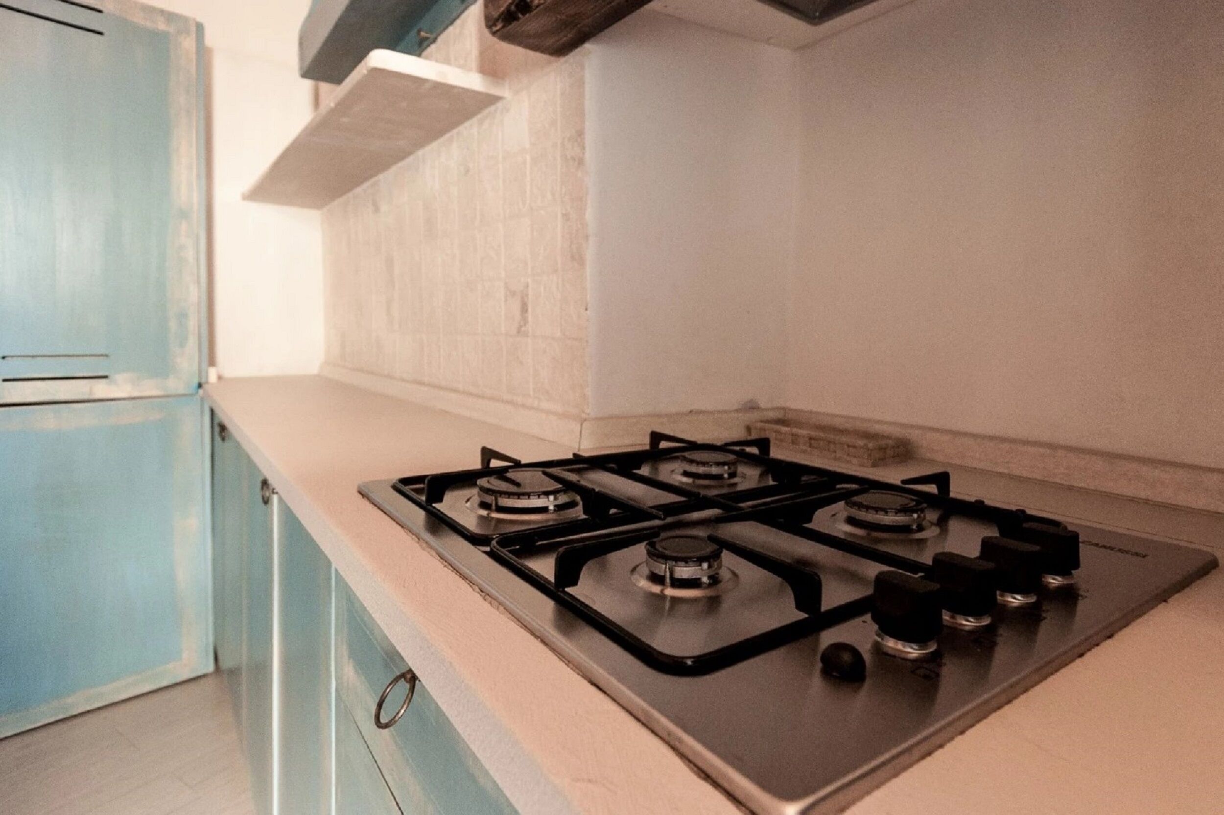 A kitchen with a gas stove, light blue cabinets, and a white countertop.