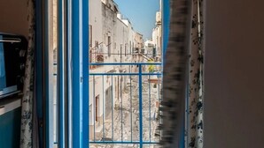 Un couloir étroit avec une porte bleue donnant sur une cour.
