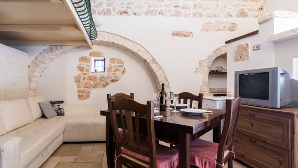 Un coin repas avec un mur en pierre, une table en bois et des chaises.